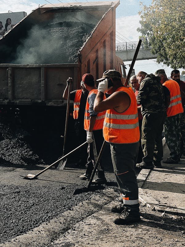 Operario realizando tareas de mantenimiento vial bajo el sol intenso, prevención de golpes de calor.